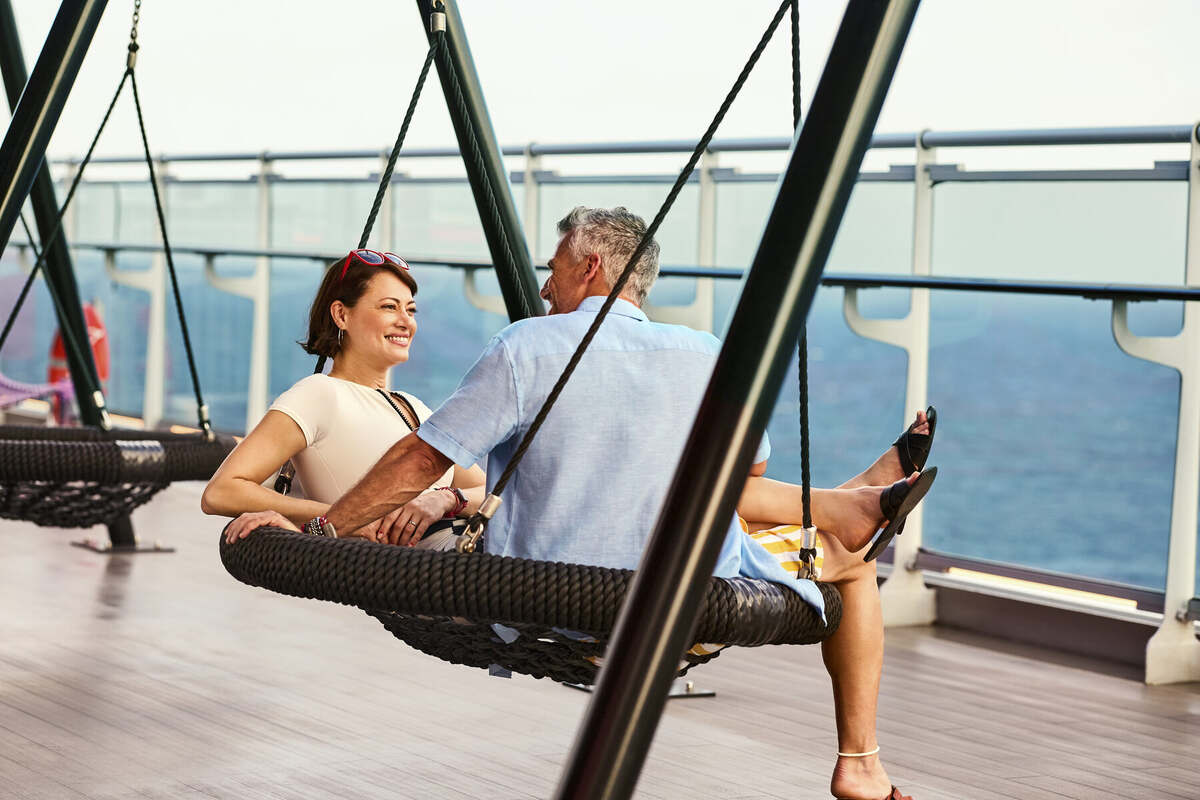 Couple relaxing on ocean-view swings on deck