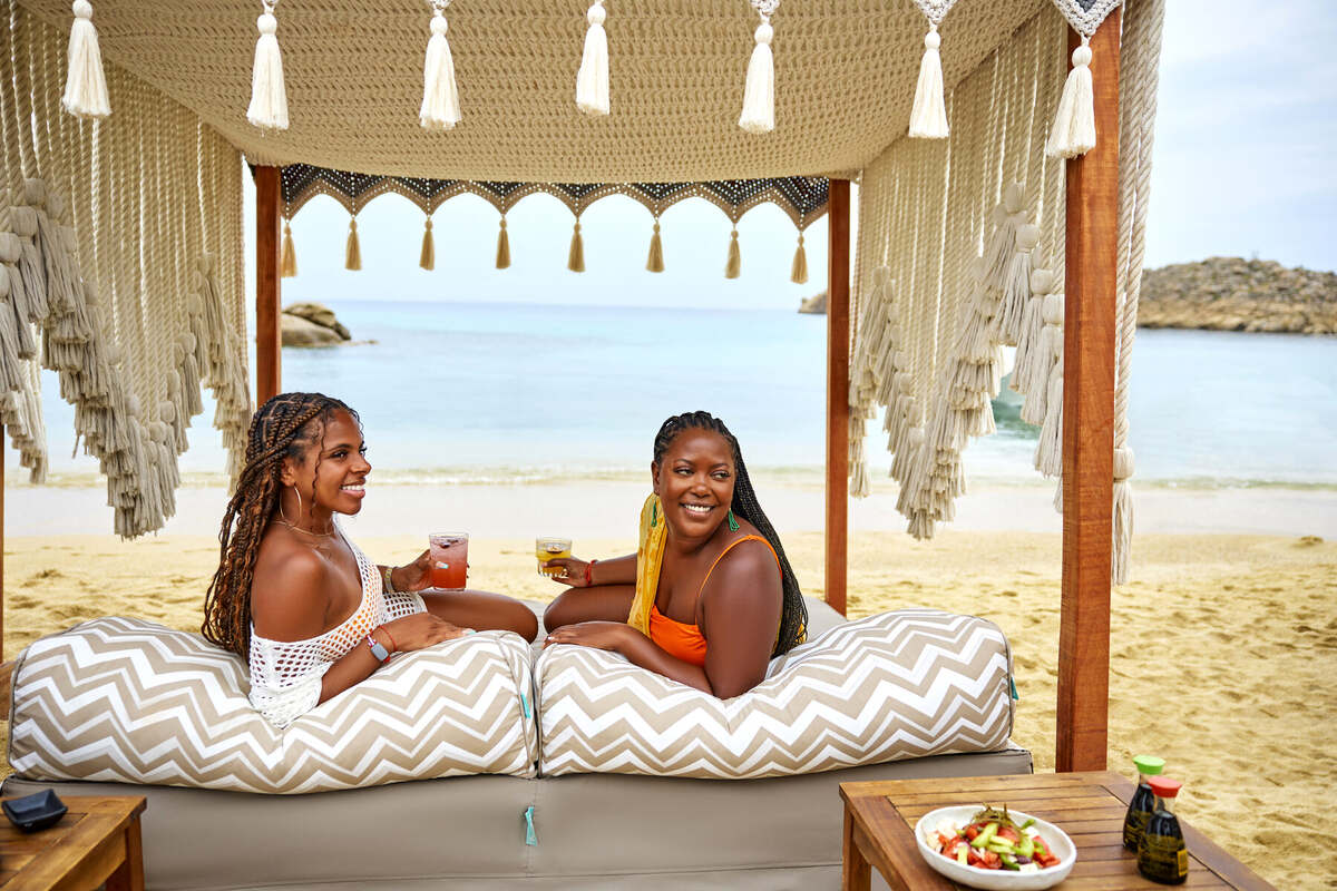 Friends relaxing in a cabana at Kalua Beach Club, Mykonos