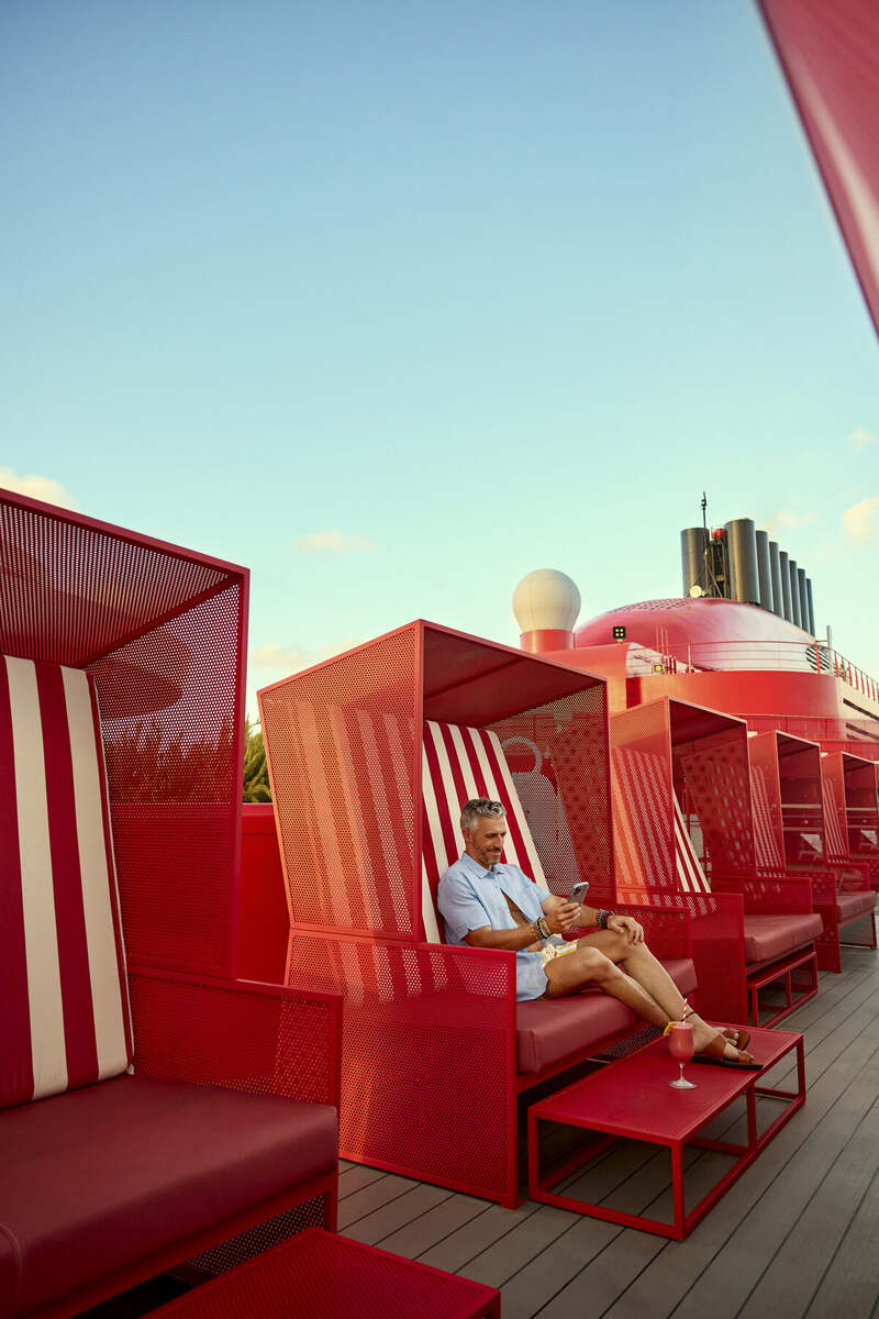 Guest relaxing in a private red cabana on deck